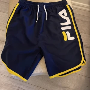 Badshorts fila  - Trendiga Fila badshorts i marinblått, hela fina och knappt använda säljes för endast 240:- 