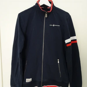 Sweatshirt sail racing - Fin tröja från sail racing med dragkedja. Marinblå med röda och vita detaljer. Fint skick. Ordinarie pris ca 1200kr