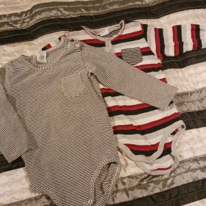 2 bodies barn - Från vänster: 1 st randig från lindex i storlek 86. 1 st röd randig i storlek 86. Båda med lång ärm. Sparsamt använda.