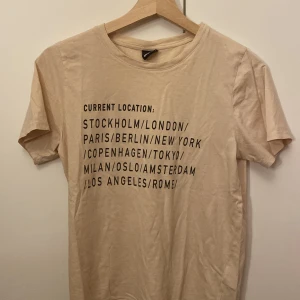 T-shirt med text - Säljer denna t-shirt med text från Gina tricot. Det som står är olika städer. Tröjan är i väldigt fint skick och jag säljer för att den inte riktigt är min stil. Tröjan är bekväm och har inga skador. 