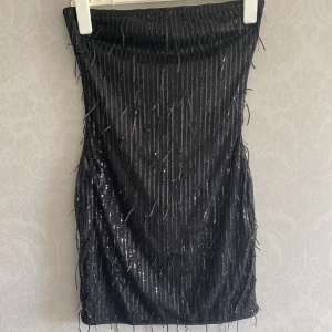 Glittrig festklänning  - Svart klänning med hängande glitter Klänningen har inga axelband  Storlek: Small  Aldrig använd, endast testad 