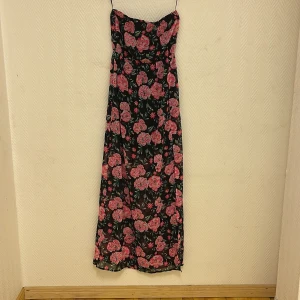 Blommig långklänning - oanvänd  - Superfin långklänning som är oanvänd. Slits på sidan. Perfekt till fest.   Köparen står för frakten. Jag ansvarar inte för postens hantering. Jag visar bild på när jag skickar paketet. Vid fler intressen av objekt kan bud över begärt ingångspris läggas