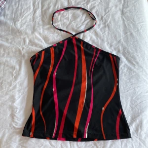 halterneck topp - en halterneck topp i svart, rosa, röd, orange och silver. snöret knyter man runt halsen i den längd man vill ha. storleken är M men passar som S. lite croppad 💗 köparen står för frakt.
