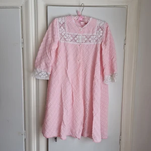 VINTAGE nattlinne / nattplagg - Ljuvt rosa nattlinne eller nattplagg (nätt "morgonrock"?) Med vit spets. Creppat tyg. Knäpps framtill med vita knappar. Uppskattas passa stl M / 40-42