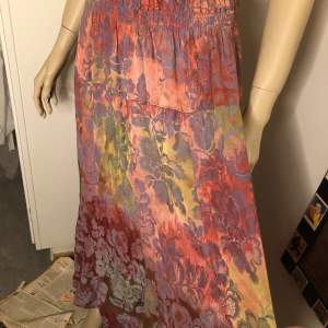 Vacker vintage lång kjol med blommor som skimrar i olika färger. Bra skick! Storlek M/L