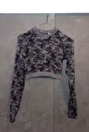 Gymshark croptop - Gymshark croptop i Camo Seamless kollektionen. Den är ganska tjock i materialet och sitter på plats! Väldigt snygg i ryggen och den har en crunches där fram. 🖤🖤🖤 (Har klippt av lappen, men annars i bra skick)