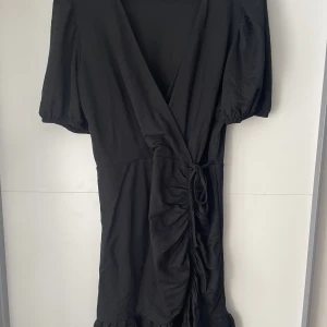 Svart klänning - Säljer en jätte söt svart klänning som går omlott från Gina tricot. Använd ca 3ggr väldigt fint skick. Har lite puffiga ärmar och ett fint fall. Perfekt sommarklänning! Strl XL🌟❤️