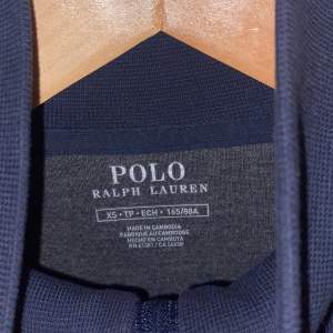 En marin-blå Polo tröja köpt ifrån Polo butiken. Har ägt den i kanske 1 år men knappt använt då jag fick den i present men ogillar färgen i min smak. Har använts cirka 4/5 gånger. Som ny!! Köpt från mans avdelningen, därav är storleken för en tjej typ S. 