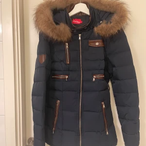 Vinterjacka. Fodrad och med äkta päls.  - Fodrad, figursydd vinterjacka från Diabless of Sweden. Metallbit på luvan och ena ärmen saknas, men inget man tänker på. Sparsamt använd. 