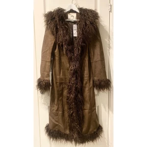 oanvänd Urban Outfitters Longline Shearling Trim Coat storlek M - Oanvänd helt ny UO Longline Shearling Trim Coat. True to size och bra fabrikat. Kappan går att stänga hela vägen med knappar på insidan som inte syns, vilket är en fin detalj. Sök upp kappan på UO hemsida för bilder på modell. Ordinarie pris 115€/ 1200kr
