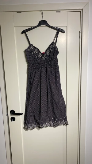 Prickig klänning  - Svart/ vit prickig klänning från Indiska i bomull. Med spets i kanterna. Vringad. Stl S Fint skick!