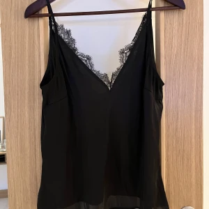 Satinlinne med spets från H&M - Så fint linne i satinliknande material från H&M med spetskant. Lite djupare i ryggen än framtill. Fint skick, hittar inget att anmärka på. Stl 36 men passar nog även 38