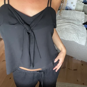 Svart linne - Ett avslappnat men ändå inte pösigt linne. Knytning fram. Perfekt längd. Köpt på Mango för flera år sen. Säljer även ett i blått! Stl Xs