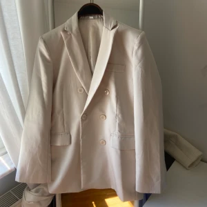 Cream vit kavaj - Cream vit kavaj, färgen är som på bilden, lite mer åtsittande i midjan, vadderade axlar, Dubbelknäppt modell, lite fodrad. Aldrig använvänd. 