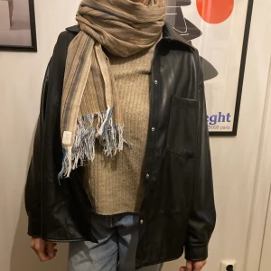 Svart skinnskjorta - Svart skjorta i fuskskinn från pull and bear. Använd 2-3 gånger, bra skick. 