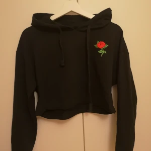 Hoodie med ros - Hoodie i tunt material. Rosen är inte tryckt utan ett påsytt märke. 
