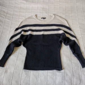 Svart/beige randig stickad tröja, storlek XS (S) - Svart och beige stickad tröja från Lindex i 100% bomull. Snygg modell som är kroppsnära runt mage och mer lös över bröstet och överarmar. Bara använd ett par gånger. Storlek XS men tror den kan passa större storlekar också.