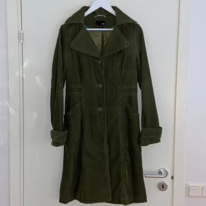H&M Manchester Kappa - En trendig manchesterkappa från H&M i färgen mossgrön i gott skick. Perfekt nu till hösten med dess figursydda modell.