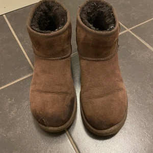 Uggs mörk bruna storlek 39 - Säljer mina Uggs då jag köpt nya. Dem är i använt skick, samt en skråma (se bild), därav det billiga priset. Frakt ingår i priset. Hör av er vid frågor💕 kom med prisförslag 