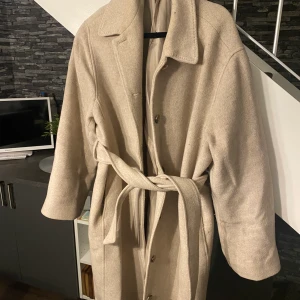 Beige kappa  - Säljer denna beiga kappa från another storys. Lite nopprig här och där men ändå fint skick. Nypris 2200. 