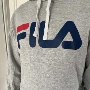 Fika hoodie - Grå hoodie från Fila. Sparsamt använd, inget att anmärka på. Ord.pris 819 kr.