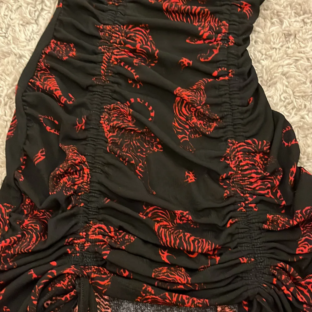 Svart klänning med röda leoparder,storlek xxs från hm. Skulle passa 160cm skulle jag säga.Den går att sjustera med snören❤️ skriv privat för mer information!👍🏼. Klänningar.
