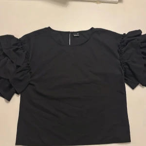 Tröja med volanger - Svart tröja med volanger på armarna 
