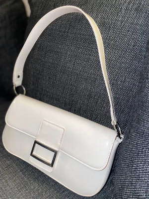 Väska - Denna väska säljs nu för att jag inte använder väskan. Väskan passar till alla sorters outfits och även köpt för ca 1 månad sen o använd ca 2 gånger. Inga trasigheter och en allmänt fräsch lack väska i vit. 