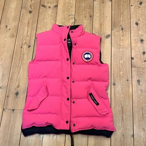 Canada Goose dunväst  - Rosa dunväst som är i mycket bra skick. Med fickor på sidorna samt dragkedja och knappar för att stänga västen. 