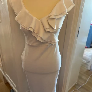 Kuvert klänning med volang stl S  - Fin vit klänning  Stl S Fint använt skick  Snyggt figursydd   Från Nelly one