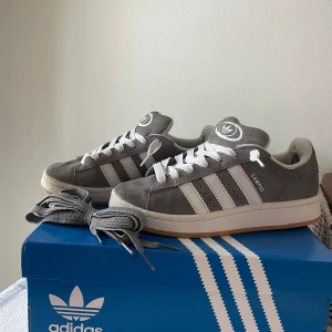 Adidas Campus 00s - Säljer mina gråa Adidas Campus 00’s. Använda men bra skick! Sitter vita snören på, gråa snören skickas med. Stl 38 2/3. 