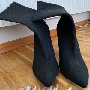 Svarta stövletter med spetsig tå - Säljer ett par eleganta svarta stövletter med spetsig tå och klack. De är i ett stickat material som ger en tight passform och en stilren look. Perfekta för höst och vinter, och funkar lika bra till fest som till vardags. klacken är 11cm , använd 1-2 gånger. spetsig tå gör att dom känns mindre därför kan kännas som en stolek mindre (40 är storleken)  🖤
