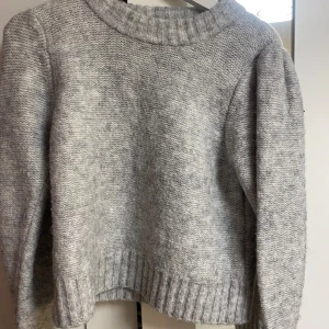 Grå stickad tröja från Lindex - Säljer en supermysig grå stickad tröja från Lindex i storlek M. Den är perfekt för höst och vinter med sin varma och bekväma design. Tröjan har långa ärmar och en ribbad kant vid halsen, ärmsluten och nederkanten. Perfekt för att hålla dig varm och snygg under de kallare månaderna! 