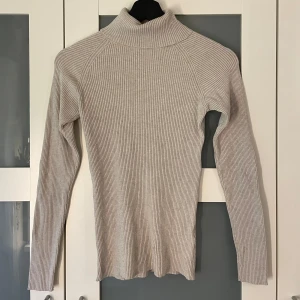 Polotröja - Beige polotröja från Cubus i storlek Xs, passar också S och en liten M beroende på hur tajt man vill ha den!   Lite tråddragning på magen, därav det låga priset. 