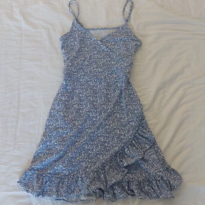 Blommig sommarklänning med volang - Säljer en superfin blommig sommarklänning💙Den är omlott framtill och har en volangkant längst ner. Knappt använd o inga defekter föruton att lappen är avklippt. Den är från Gina young, skulle säga att den passar xxs och xs.