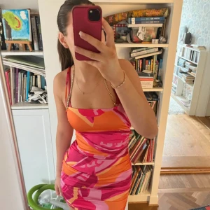 Färgglad klänning med mönster - Säljer en superfin klänning med ett färgglatt mönster i rosa, orange och rött. Klänningen är tight och har smala axelband. Perfekt för sommarens fester! 💃