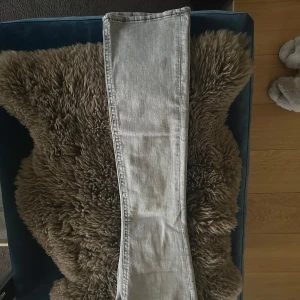 Grå jeans från Gina Tricot - Snygga grå jeans från Gina Tricot med låg midja och raka ben. Perfekta för en avslappnad stil. De har klassiska femficksdetaljer och knappar vid fickorna. Helt nya