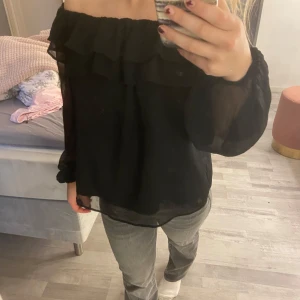 Svart offshoulder blus - Snygg svart offshoulder blus med volangdetaljer. Från Gina Young knappt använd så i nyskick! 
