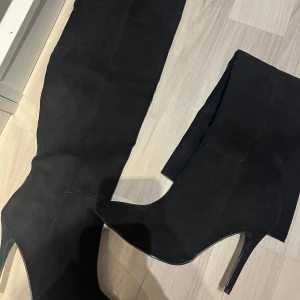 Overknee Boots  - Svarta boots från Nelly i storlek 37. Cirka 10 cm hög klack, rätt så smal klack. Testade endast en gång. Finns små defekter då de stått i garderoben i några år. Säljer då de inte passar mig. (Passar ej breda vader & fötter). 