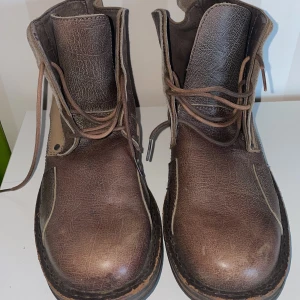 Bruna boots med snörning Bianco man - Snygga bruna boots i skinn med snörning och robust sula. De har en kombination av brunt och beige material vilket ger en stilren look. Perfekta för höst och vinter.