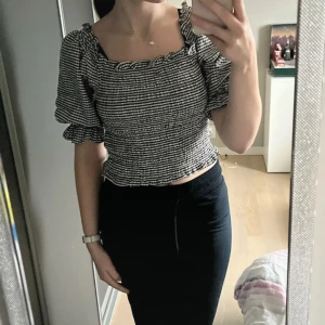 Svartvit rutig topp - Säljer en snygg svartvit rutig topp med volangdetaljer. Toppen har en offshoulder-design med korta ärmar. Är använd typ 5 gånger så är som nyskick.  
