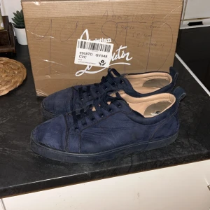 Blå sneakers från Christian Louboutin - Snygga blå sneakers från Christian Louboutin med den ikoniska röda sulan. Skorna har snörning och är tillverkade i ett stilrent material som ger en lyxig känsla. Perfekta för dig som vill ha en exklusiv touch på din stil. F4KE, rengöring skeds innan frakten skriv vid fundering  Allt OG kmr med