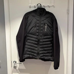 Svart Sail Racing Jacka  - Säljer en svart dunjacka från Sail Racing i storlek medium. Jackan har en stilren design. Perfekt för våren och hösten, ända fel är att ena lappen på insidan har släppt annars topp skick,