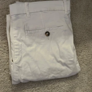 Vita shorts från Dressmann - Säljer ett par stilrena vita shorts från Dressmann. Byxorna har en klassisk design med knappstängning och bälteshällor. Perfekta för en avslappnad men ändå uppklädd look.