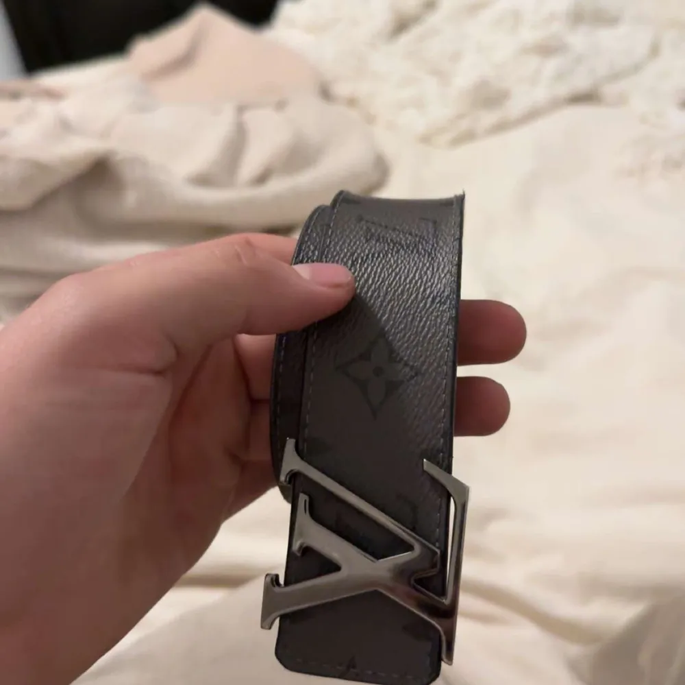 Snyggt grått bälte från Louis Vuitton med det klassiska LV-mönstret. Bältet har ett stilrent spänne i silverfärg med LV-logotypen. Perfekt för att ge din outfit en lyxig touch. . Muu.