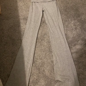 Grå yoga byxor från Gina Tricot - Snygga grå yoga byxor från Gina Tricot i en mjuk och bekväm stil. Byxorna har en bootcut design som ger en trendig look. Perfekta för en avslappnad dag eller en stilren outfit.