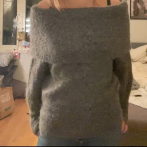 Grå offshoulder tröja från H&M - Mysig grå offshoulder tröja från H&M. Perfekt för kyliga dagar med sin fluffiga och bekväma design. Tröjan har långa ärmar och en bred krage som kan bäras ned över axlarna.