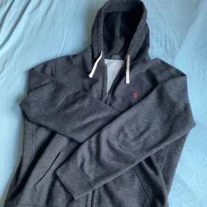 Mörkgrå hoodie från Polo Ralph Lauren - Säljer en mörkgrå zip up hoodie från Polo Ralph Lauren med en lurvig och skön insida, finns inga defekter och är i princip ny skick.