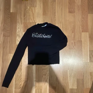 Svart tröja med text från H&M - Säljer en svart tröja från H&M med texten 'Célébrité' i glittriga stenar på framsidan. Tröjan har långa ärmar och en croppad passform. 