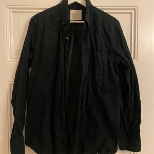 Mörkgrön skjorta från A Day's March - Snygg mörkgrön Manchester skjorta från A Day's March med klassisk design. Skjortan har långa ärmar och knappar framtill. Perfekt för en stilren look.